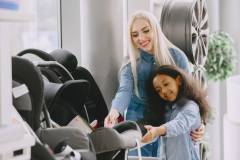 Caucasian mother with african daughter in a car salon